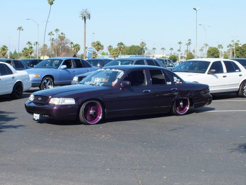 Lowered dark purple Ford sedan on custom wheels parked in a sunny lot
