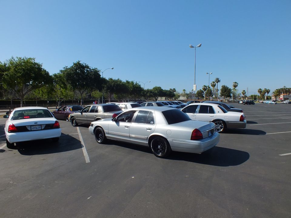Silver sedan on black wheels parked among white and gray cars in a wide lot
