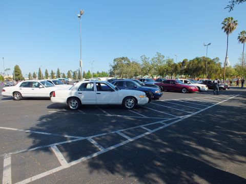White full-size sedan parked among other cars in a sunny open lot