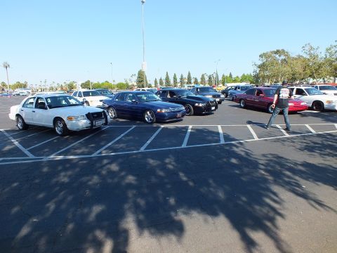 White and dark blue full-size sedans parked with a person walking by