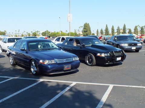 Dark blue Ford sedan beside a black sedan with push bar in a parking lot