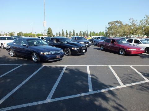 Blue, black, and maroon full-size sedans parked in a sunlit asphalt lot