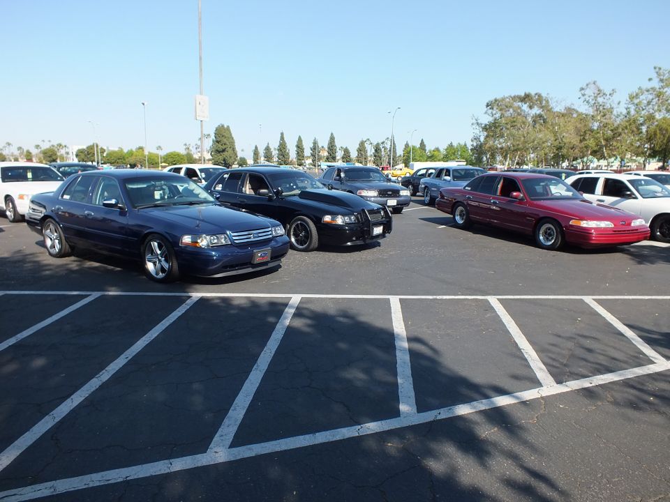 Blue, black, and maroon full-size sedans parked in a sunlit asphalt lot