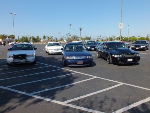 Silver Ford sedan, blue sedan, and black sedan with push bar in a lot