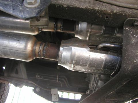 1988 Ford Bronco - Underbody view of a dual-exhaust setup showing two freshly welded stainless catalytic converters running alongside the frame rail and trans…