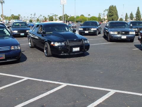 Blacked-out full-size sedan with push bar parked among other cars in a lot