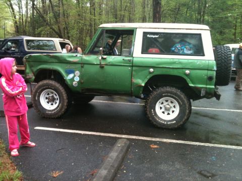 1992 Ford Bronco - This green Ford Bronco, likely from the late 1970s, is parked next to another Bronco in a wooded area.