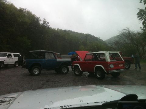 1992 Ford Bronco - Multiple Ford Bronco SUVs are parked together on a rainy day.