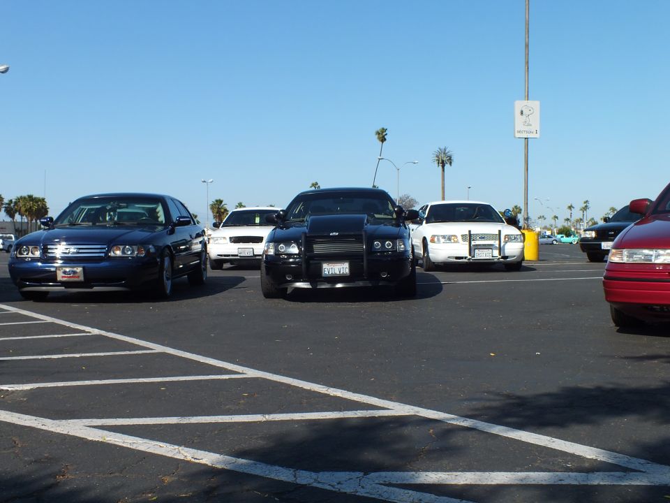 Dark sedans and a black Dodge Charger parked across an empty paved lot