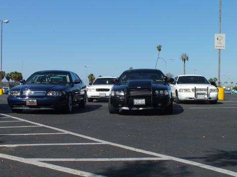 Dark blue sedan, black Dodge Charger and white sedans parked in a lot