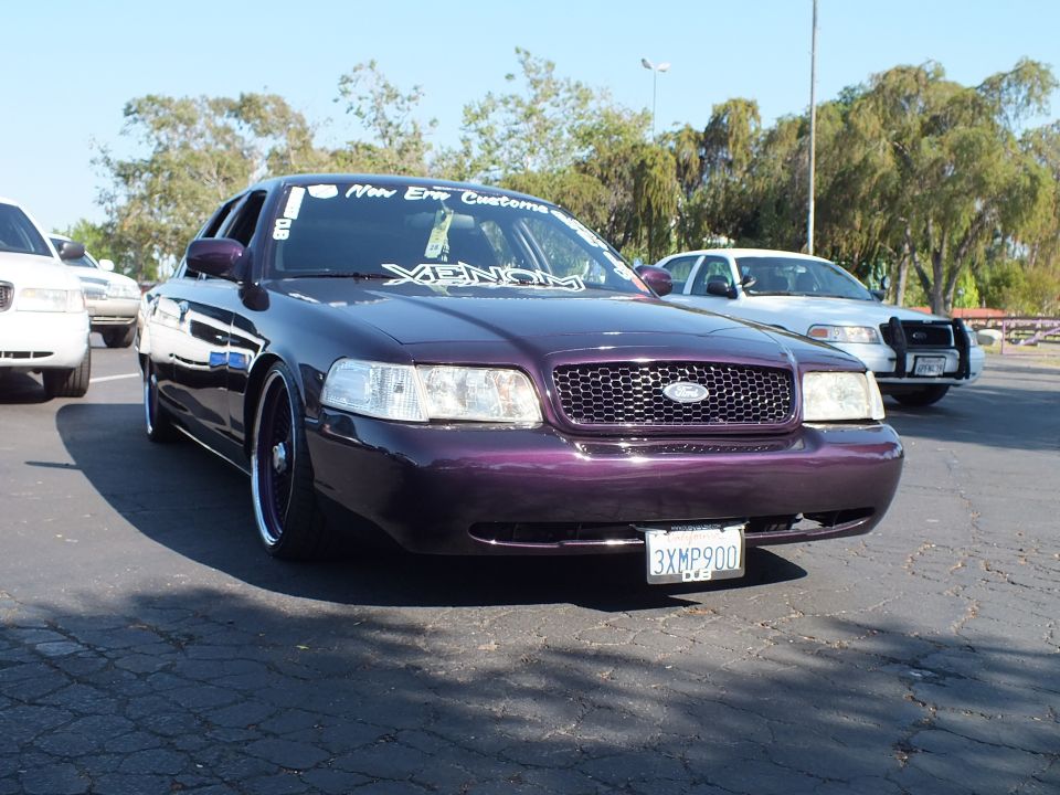 Lowered dark purple Ford Crown Victoria with chrome wheels, front view