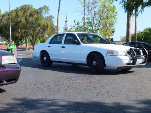 White Ford Crown Victoria with push bar viewed from the side in a lot