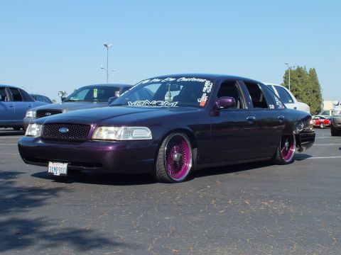 Lowered dark purple Ford Crown Victoria with pink-lipped wheels, front