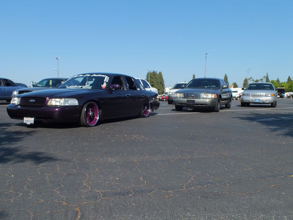 Lowered dark purple Ford Crown Victoria parked among other cars