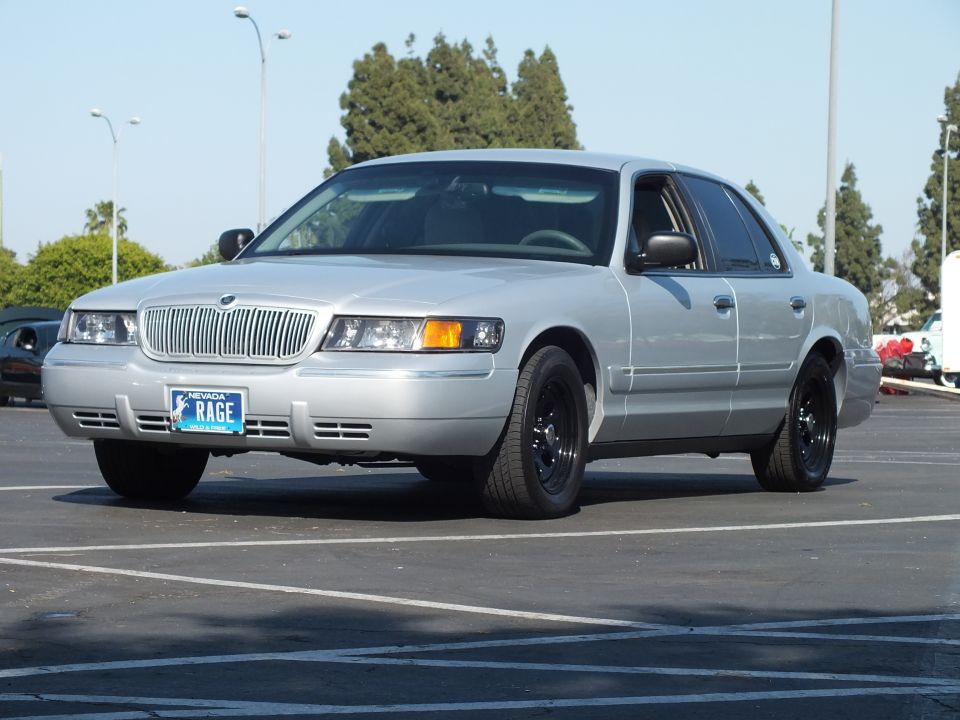Silver Mercury Grand Marquis with black wheels parked, front three-quarter