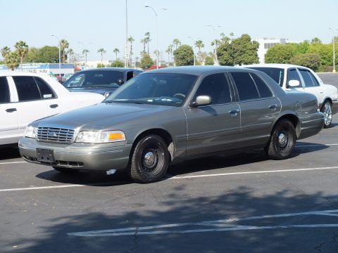 Olive-gold Ford Crown Victoria with black steel wheels, front three-quarter