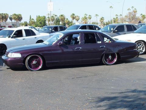 Lowered dark purple Ford Crown Victoria with chrome wheels, side view