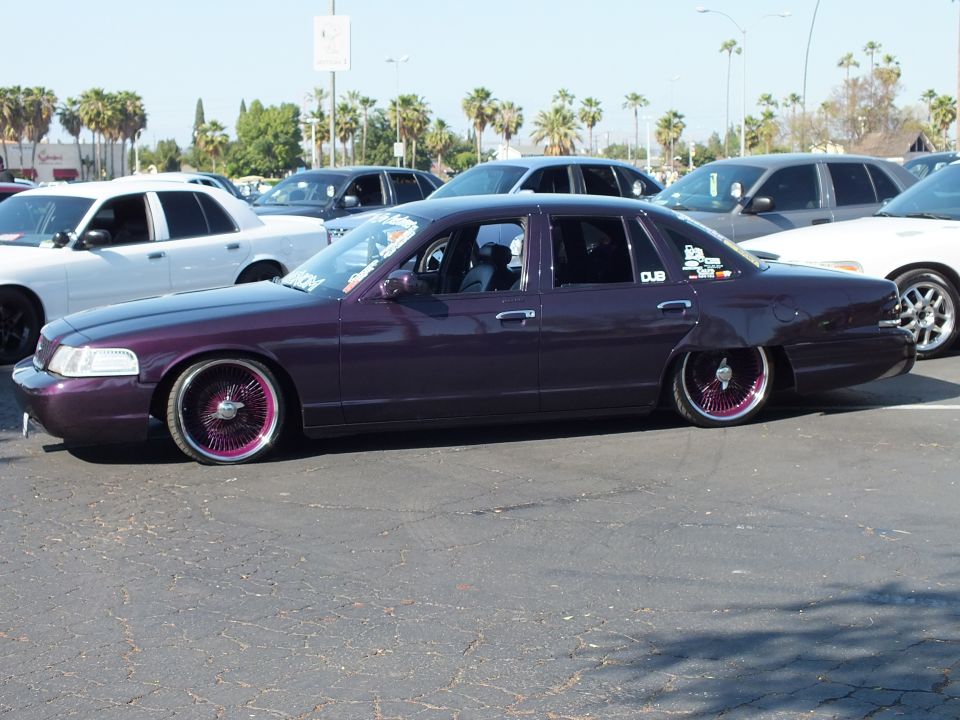 Lowered dark purple Ford Crown Victoria with chrome wheels, side view