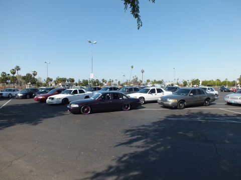 Maroon slammed sedan beside a silver sedan in a busy parking lot