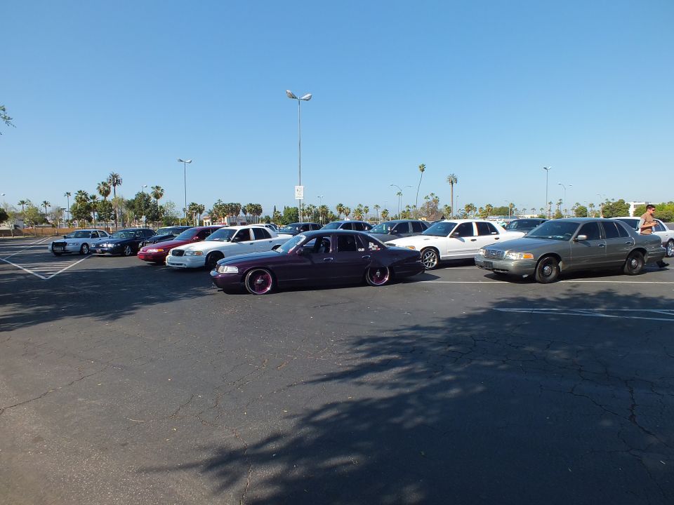 Maroon lowered sedan parked in a wide lot under clear sky