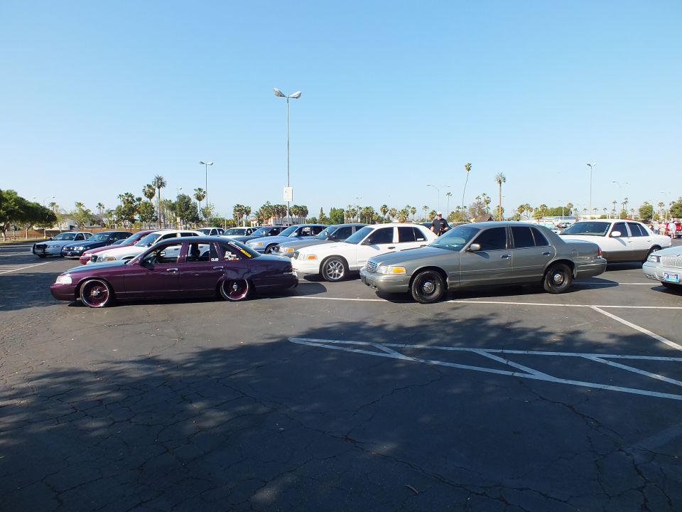 Maroon slammed sedan beside a tan sedan in a large parking lot