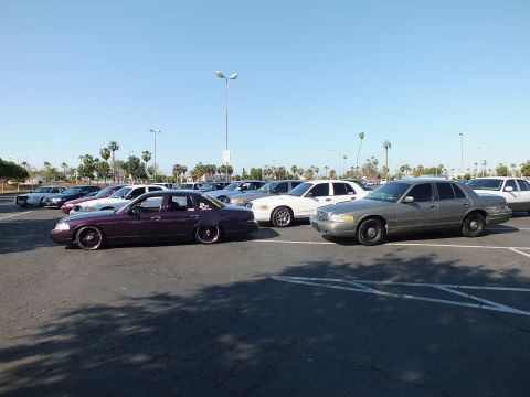 Maroon slammed sedan and tan sedan in a wide parking lot