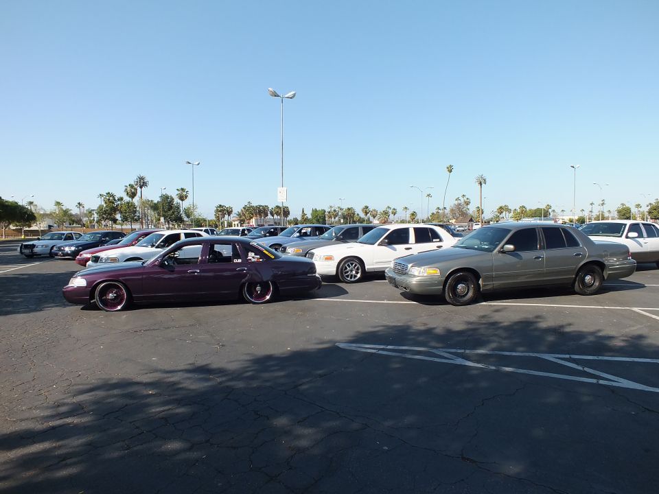 Maroon slammed sedan and tan sedan in a wide parking lot