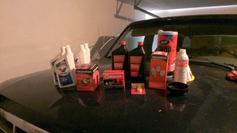 1994 Ford Bronco - Various automotive maintenance supplies are laid out on the hood of a vehicle.