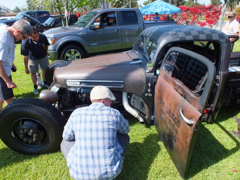 2003 Ford Crown Victoria - front of a rust-patina Ford rat rod truck with its door open and hand-painted lettering as a man crouches beside it.