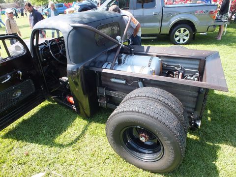 2003 Ford Crown Victoria - open rear bed of a black rat rod truck reveals a fuel tank and dual rear wheels with chrome lug caps.