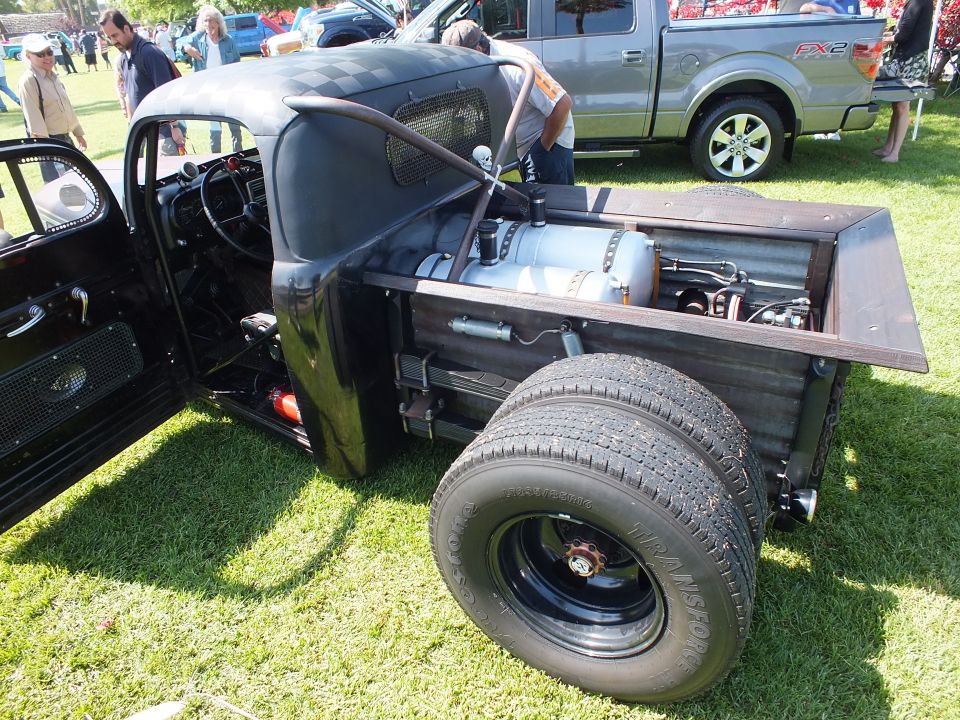 Rear bed of a rat rod truck showing dual rear wheels and fuel tank