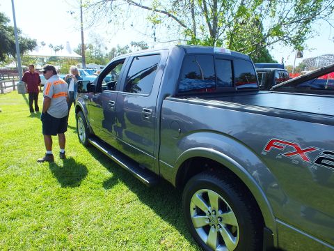 2003 Ford Crown Victoria - gray Ford F-150 FX2 crew-cab pickup is shown in profile on grass as a man stands beside it at a show.