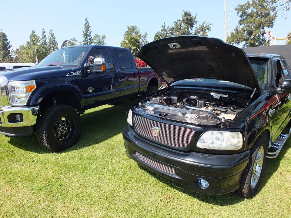 Black Ford F-150 with hood up beside a lifted dark Ford Super Duty