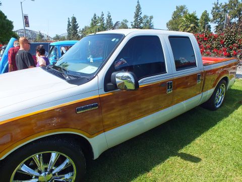 2003 Ford Crown Victoria - Side view of a customized white Ford crew-cab pickup showing wood-grain lower panels, chrome mirror, and polished wheels on a show field.
