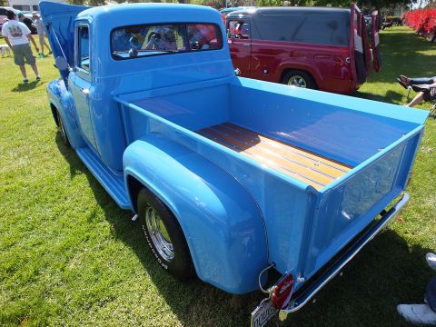 2003 Ford Crown Victoria - Rear three-quarter view of a light-blue classic Ford stepside pickup showing its wood-plank bed floor and chrome wheels on grass.