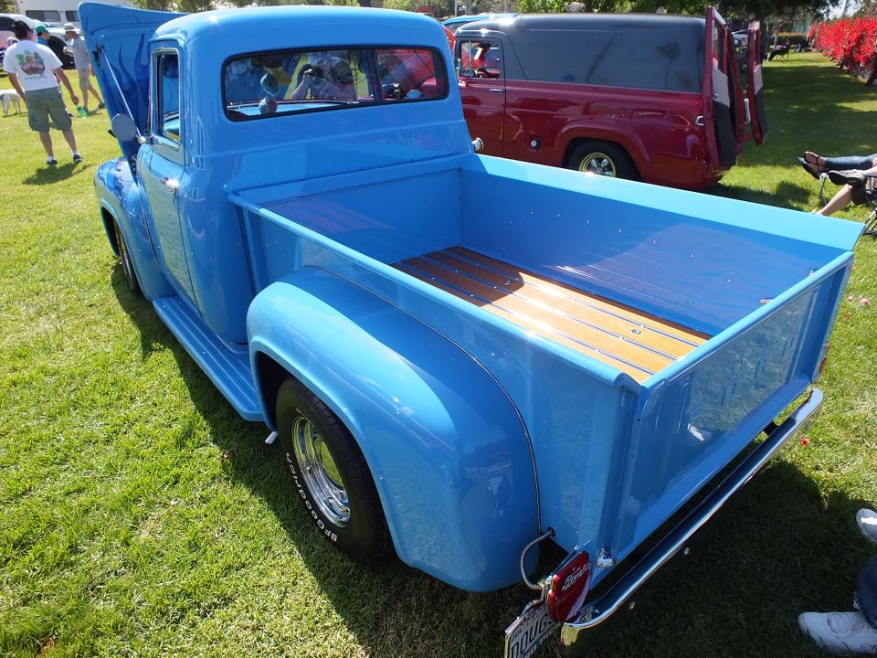 Rear three-quarter of blue classic Ford pickup with wood-plank bed floor
