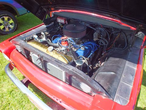 2003 Ford Crown Victoria - Close-up of a red classic truck's engine bay showing a round air filter, blue spark-plug wires and a front-mounted intercooler core.