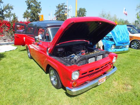 2003 Ford Crown Victoria - bright-red classic Ford pickup with an open hood and an open suicide door sits on grass at a car show next to a flamed blue truck.