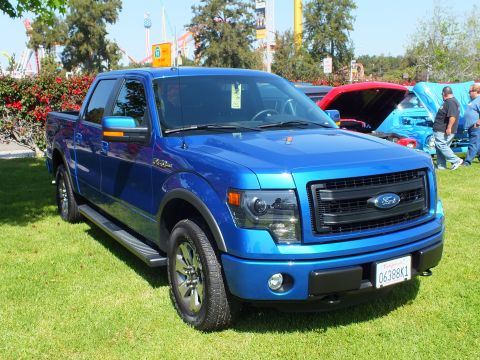 2003 Ford Crown Victoria - blue Ford F-150 FX4 crew-cab pickup with a California license plate parked on grass at a sunny car show.