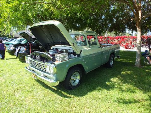 2003 Ford Crown Victoria - light-green classic Ford stepside pickup with raised hood shows a chrome-topped engine on a grassy car-show lawn.