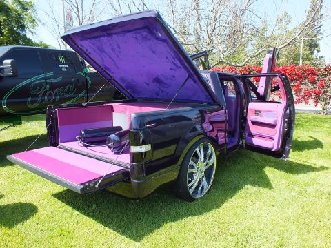 2003 Ford Crown Victoria - rear of a custom show truck reveals a purple-velvet lined raised lid over a bright pink bed and a folded-out tailgate.