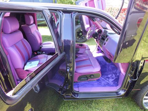 2003 Ford Crown Victoria - Both doors open on a custom truck reveal a full purple-and-pink leather interior with matching steering wheel and shag carpet.