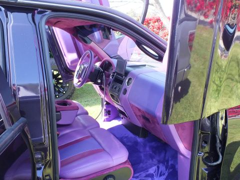 2003 Ford Crown Victoria - front cabin of a custom truck shows lavender-and-pink leather seats, a color-matched dash and a small custom steering wheel.