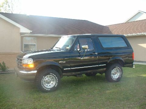 1995 Ford Bronco - This black 1995 Ford Bronco is parked on a grassy lawn in front of a house.