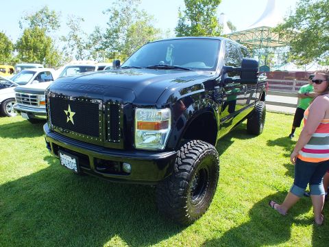 2003 Ford Crown Victoria - black lifted Ford Super Duty crew cab with a star-emblem grille and large off-road tires displayed on a show lawn.