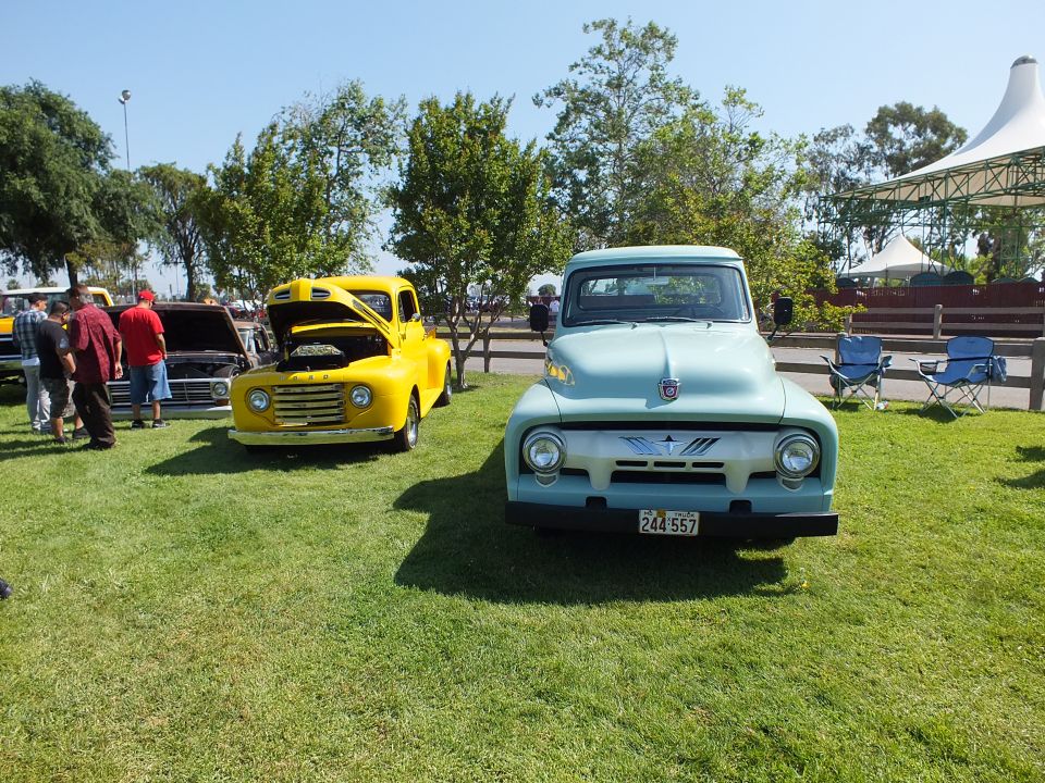 Light blue and yellow vintage Ford pickups parked on grass at a show