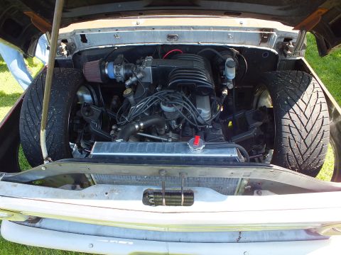 2003 Ford Crown Victoria - Open front-end of a customized vintage pickup showing a swapped fuel-injected V8, red cone intake and a wide spare tire beside the radiator.