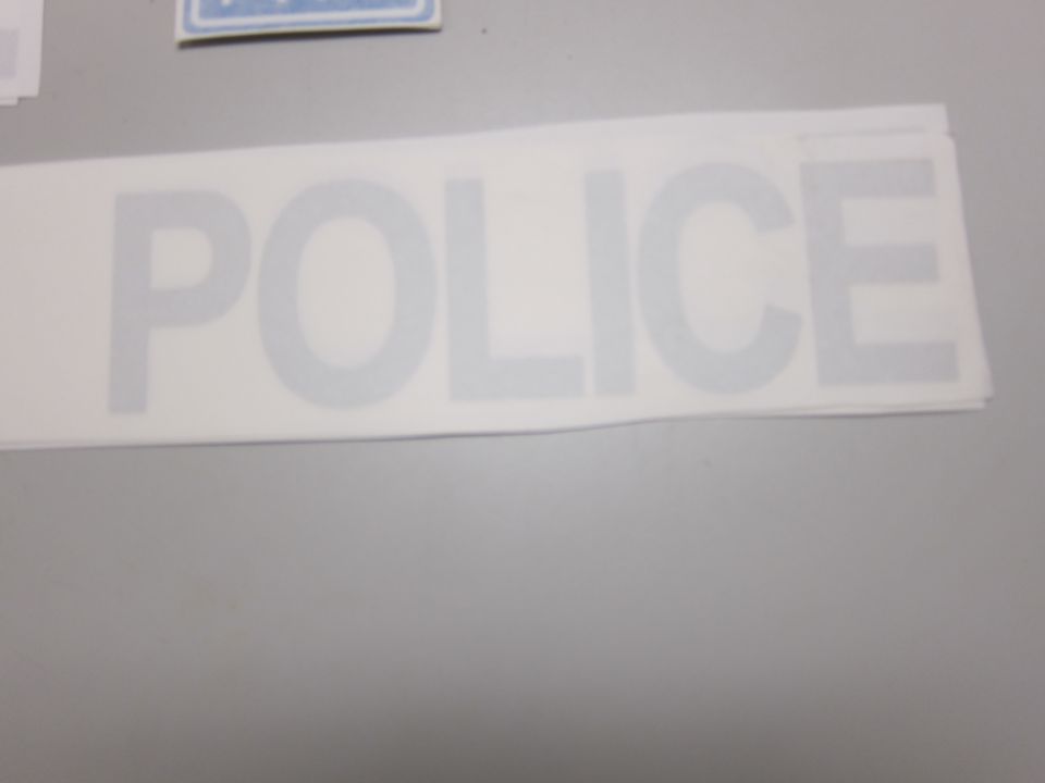 White decal with large gray letters spelling POLICE