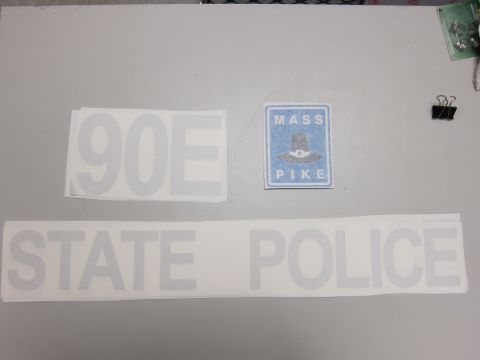 1991 Ford LTD Crown Victoria - Decals for a Massachusetts State Police vehicle are laid out on a flat surface, including the words 'STATE POLICE' and '90E'.