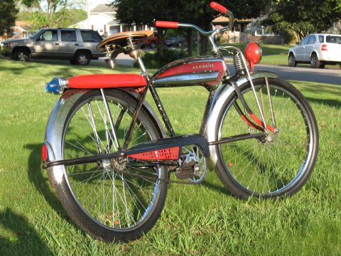 1994 Ford Bronco - A vintage Schwinn bicycle with chrome fenders and red accents sits on a grassy lawn, with houses and vehicles in the background.